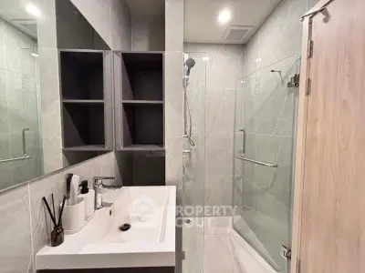 Modern bathroom with sleek shower and stylish sink in contemporary apartment.