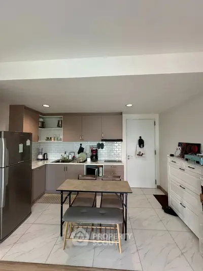 Modern kitchen with sleek cabinetry and stainless steel appliances in a cozy apartment setting.