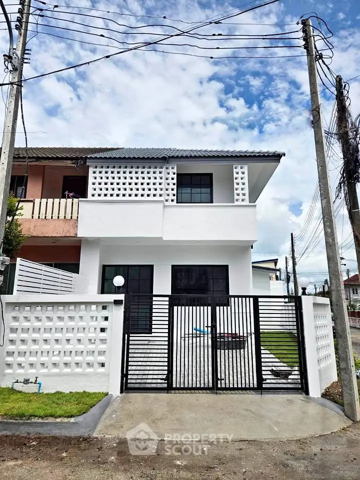 Modern two-story white house with unique facade and gated entrance in a suburban neighborhood.