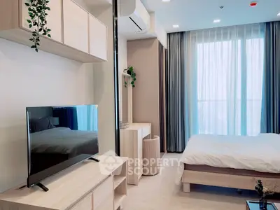 Modern bedroom with TV and large window offering natural light