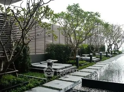 Luxurious rooftop garden with modern lounge chairs and serene water feature.