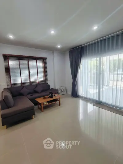 Spacious living room with modern sofa and large windows offering natural light.