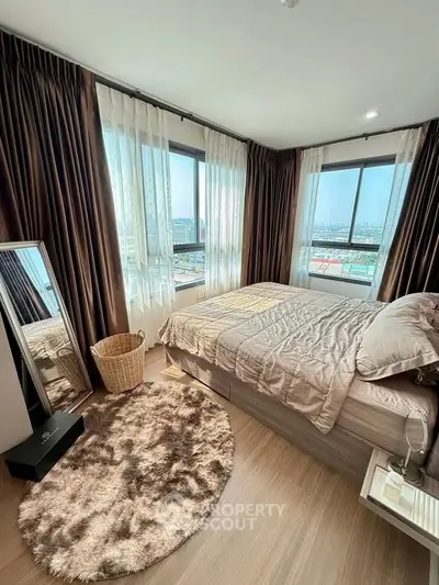 Spacious bedroom with large windows offering stunning city views, featuring elegant decor and cozy ambiance.