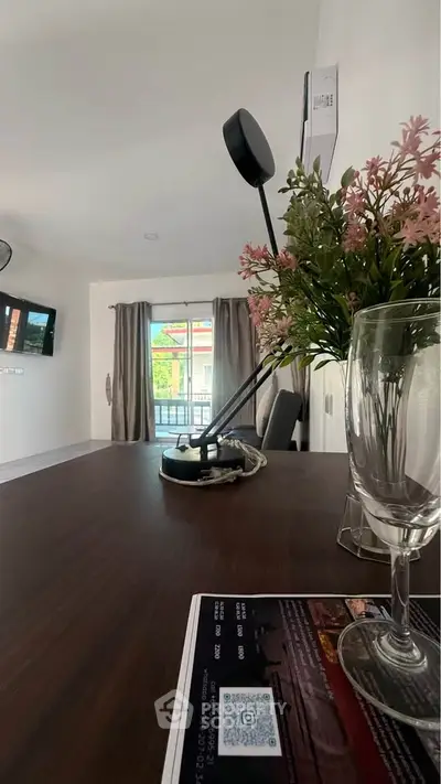 Modern living room with stylish decor and balcony view, featuring elegant lighting and fresh flowers.