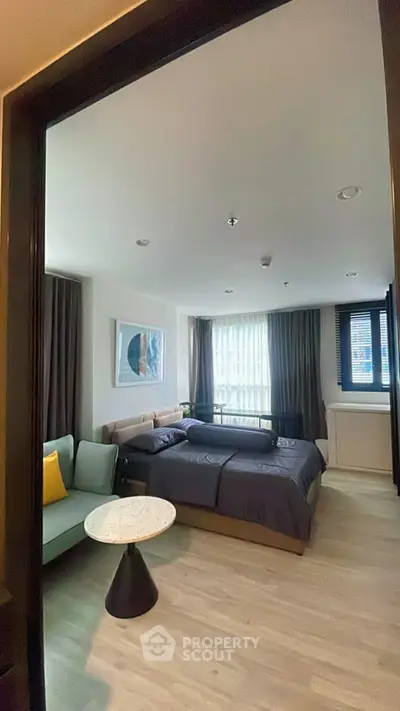 Modern bedroom with cozy seating and large window in stylish apartment