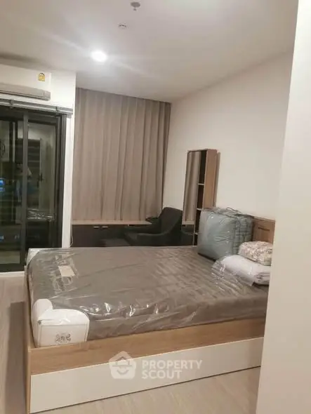 Modern bedroom with large window and stylish furnishings in a contemporary apartment.