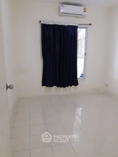Spacious empty room with tiled floor and air conditioning, ready for customization.