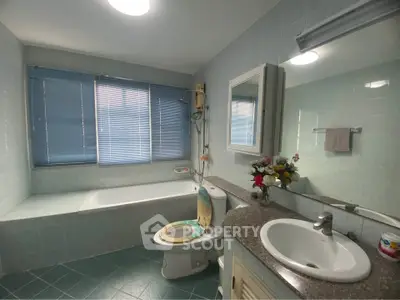 Spacious bathroom with bathtub and modern fixtures, featuring large windows and elegant tile design.