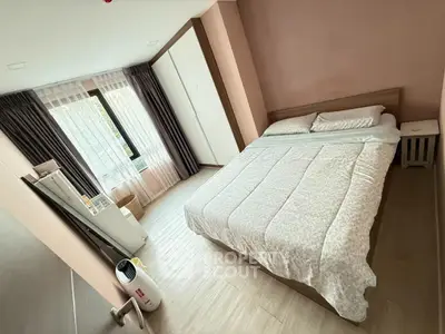 Cozy bedroom with large window and modern furnishings in a stylish apartment.