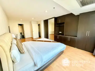 Spacious bedroom with modern wooden wardrobe and cozy bed in elegant apartment