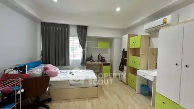Modern bedroom with stylish furniture and ample natural light, featuring a cozy workspace and vibrant decor.