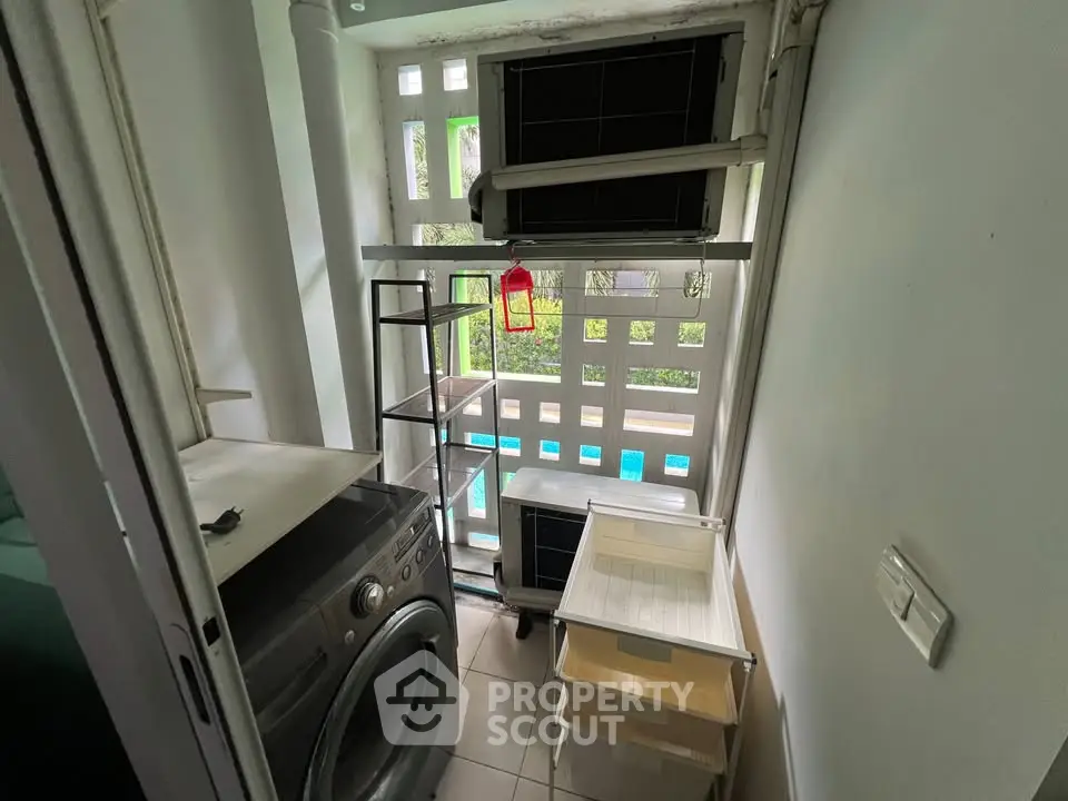 Compact laundry area with washing machine and storage shelves, overlooking a pool view.