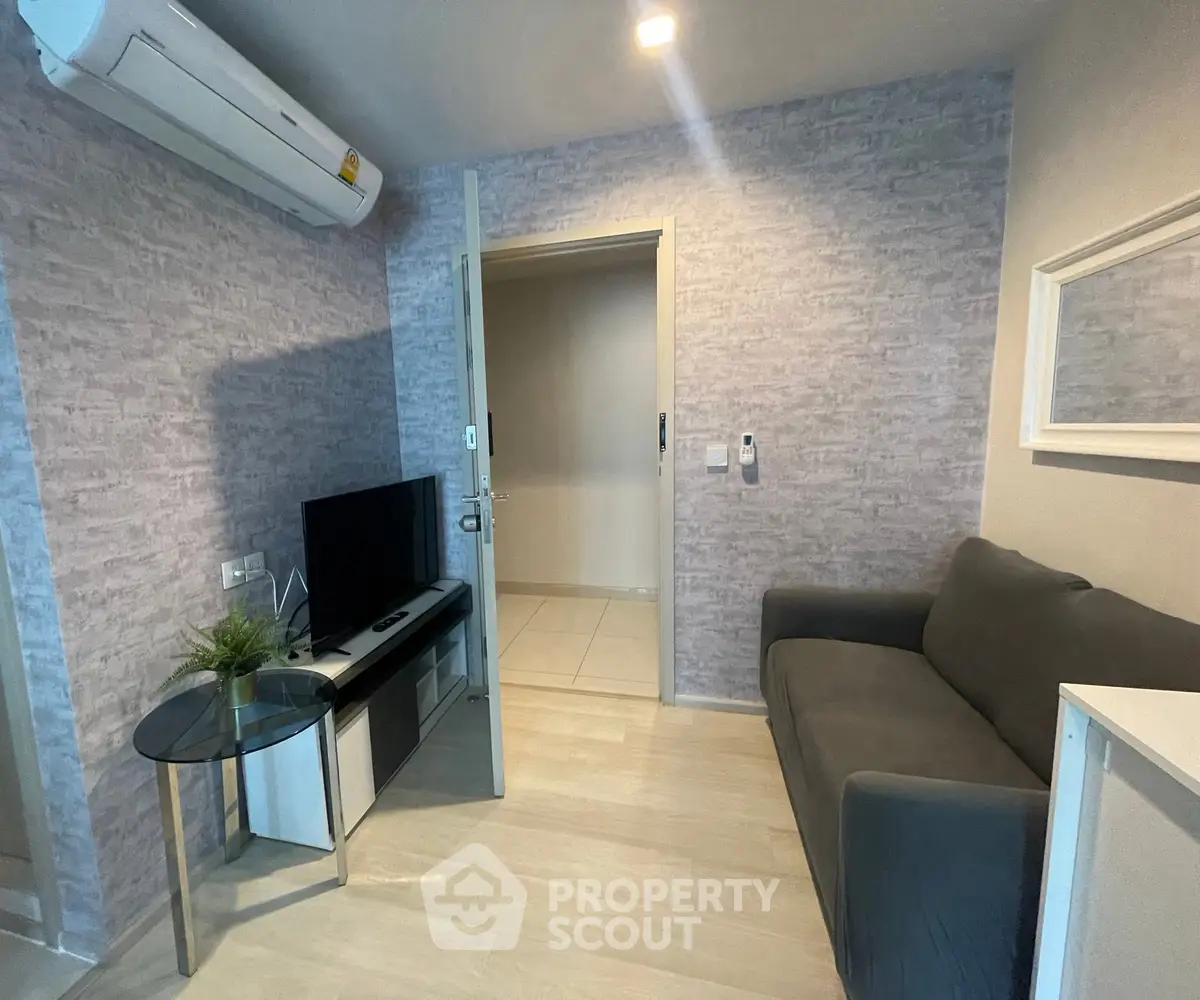 Cozy living room with modern decor, featuring a comfortable sofa, TV, and air conditioning unit.