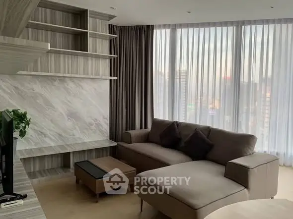Modern living room with stylish sofa and large windows offering city views.