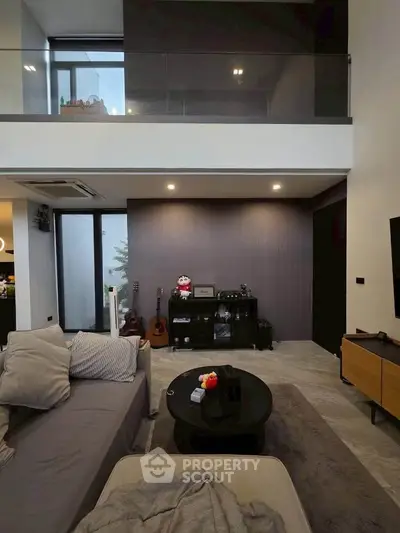 Modern living room with high ceiling and stylish decor, featuring a cozy sofa and entertainment area.