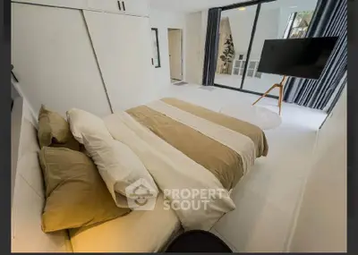 Modern bedroom with stylish decor and large TV, featuring a cozy bed and sleek design.