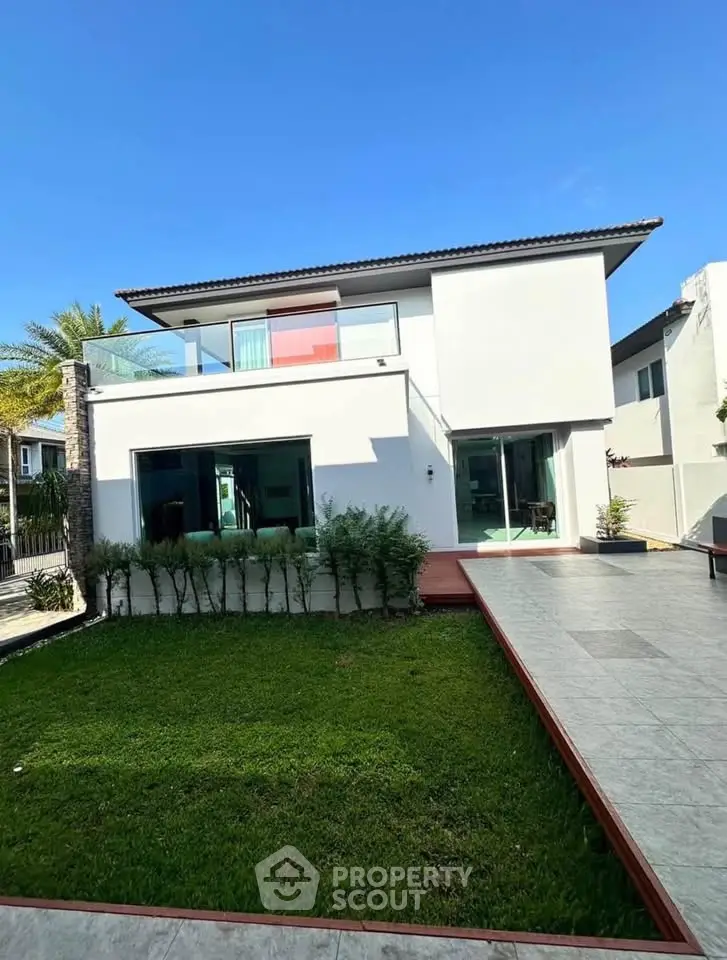 Modern two-story house with spacious balcony and lush green lawn