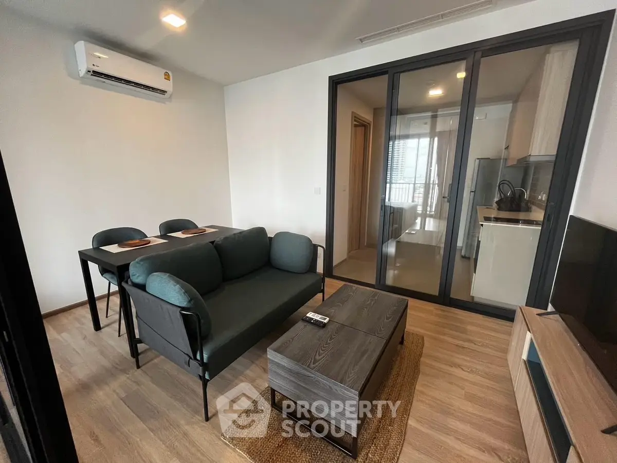 Modern living room with sleek furniture and open kitchen layout in a stylish apartment.