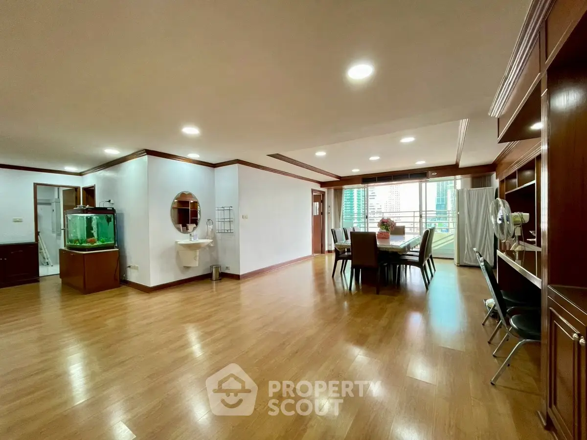 Spacious open-plan living and dining area with wooden flooring and city view.