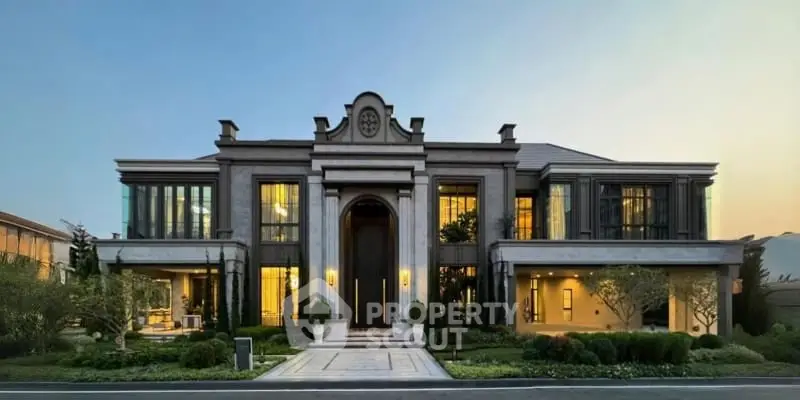 Luxurious mansion with grand entrance and elegant landscaping at sunset.
