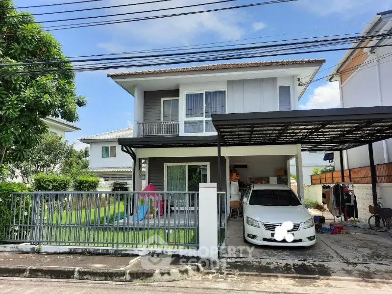 Charming two-story house with carport and lush garden in suburban neighborhood.