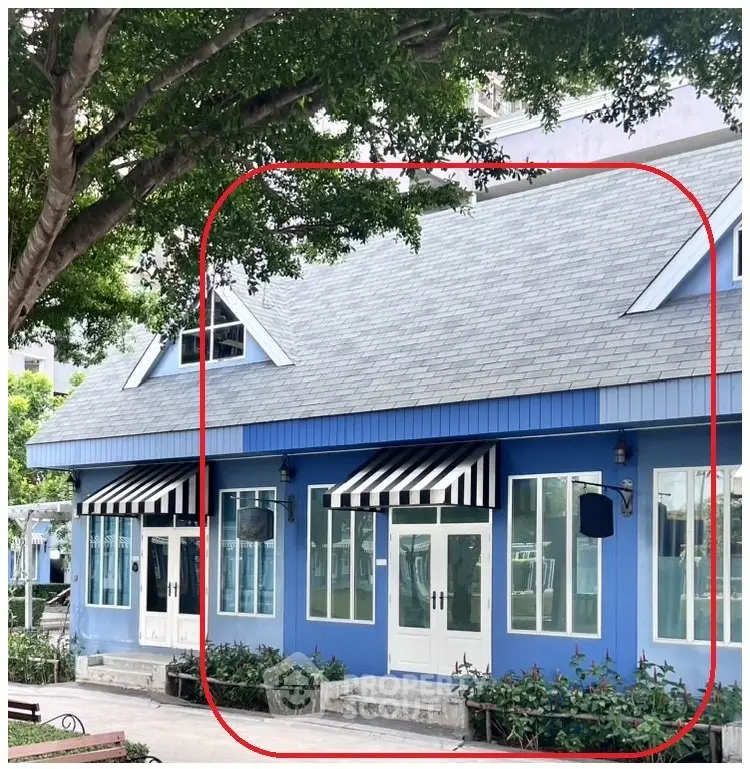 Charming blue building with striped awnings and lush greenery