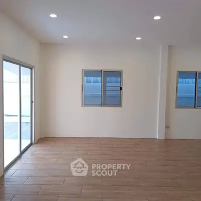 Spacious empty room with wooden flooring and large windows