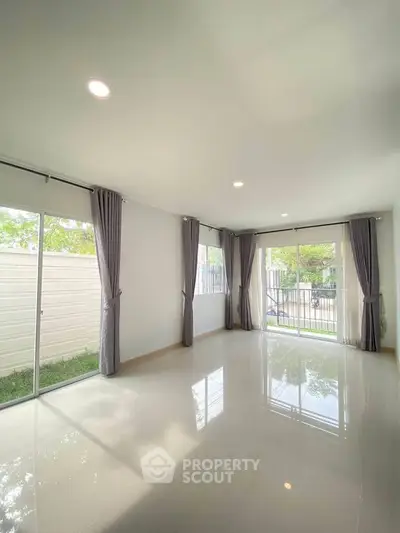 Spacious living room with large windows and garden view, perfect for natural light lovers.