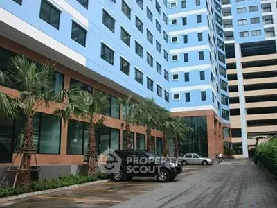 Modern high-rise building with parking area and palm trees, showcasing urban living.