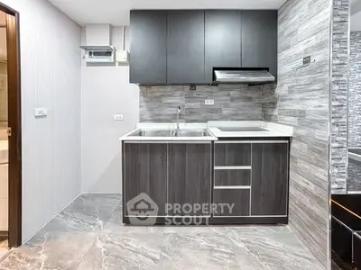 Modern kitchen with sleek cabinetry and stylish backsplash in a contemporary apartment.