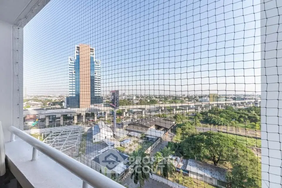 Stunning cityscape view from a high-rise balcony with safety netting, showcasing urban living.