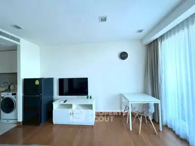 Modern living room with TV, fridge, and washing machine in open layout.