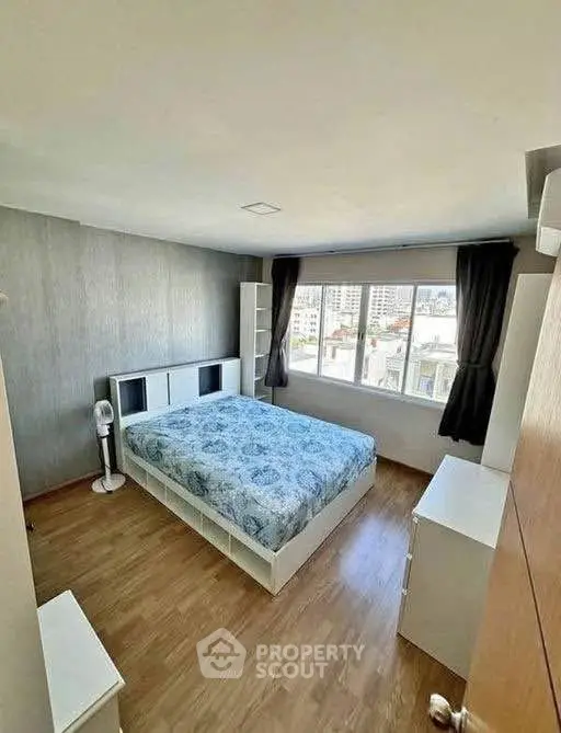 Spacious bedroom with large window and modern furnishings, offering a bright and inviting atmosphere.