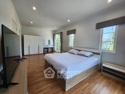 Spacious modern bedroom with large windows and wooden flooring