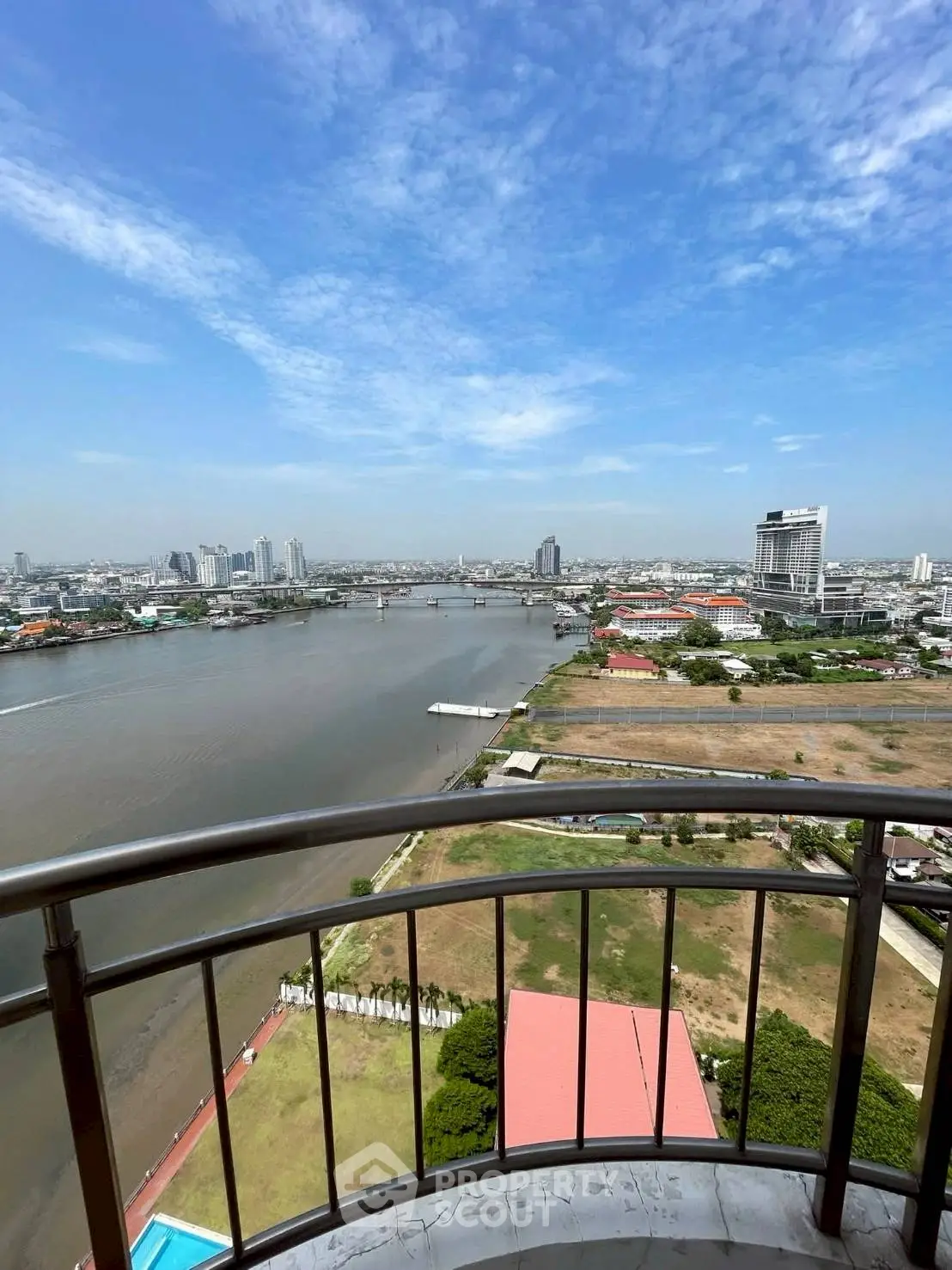 Stunning river view from high-rise balcony with cityscape and clear blue sky.