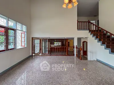 Spacious two-story living room with elegant staircase and large windows