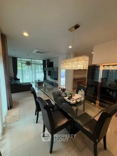 Elegant living and dining area with modern furnishings and chandelier lighting.