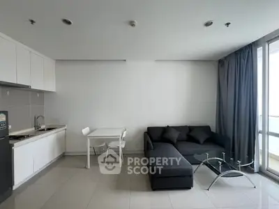 Modern living room with sleek kitchen and cozy seating area in a bright apartment.