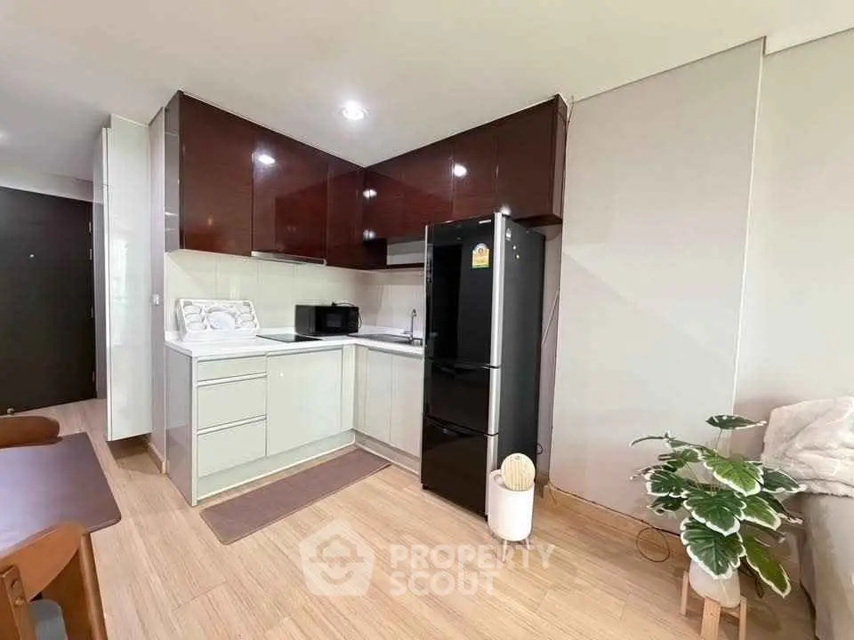 Modern kitchen with sleek cabinetry and black fridge in cozy apartment