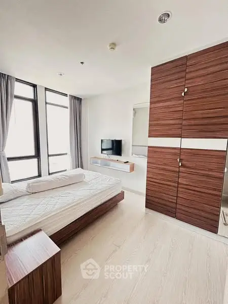 Modern bedroom with large windows and wooden wardrobe in stylish apartment