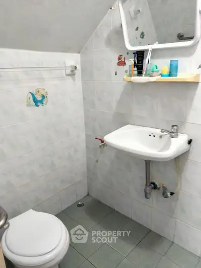 Compact bathroom with white tiles and corner sink, ideal for small spaces.