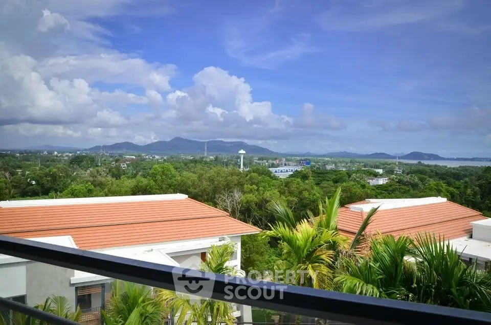 Stunning panoramic view from a balcony overlooking lush greenery and distant mountains.