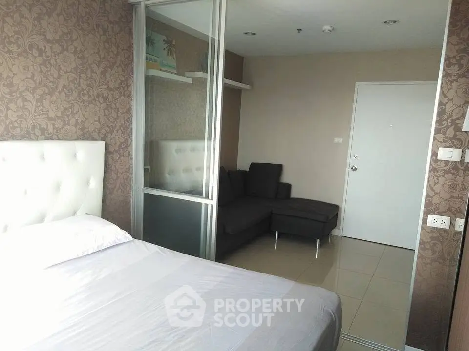 Modern bedroom with elegant wallpaper and cozy seating area in a stylish apartment.