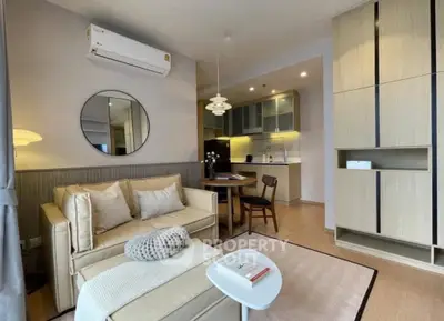 Modern living room with cozy seating and stylish kitchen in open layout apartment.