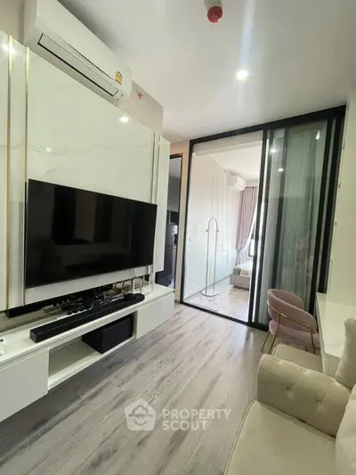 Modern living room with sleek TV setup and sliding glass doors leading to a cozy bedroom.