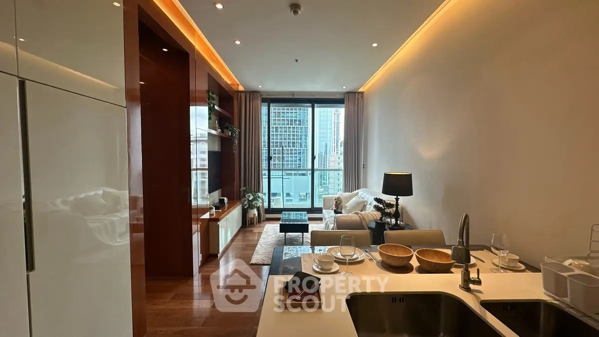 Modern living room with open kitchen and city view, featuring elegant decor and natural lighting.