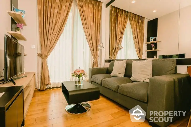 Cozy living room with plush gray sofa, elegant drapes, and gleaming hardwood floors, perfect for comfortable urban living.