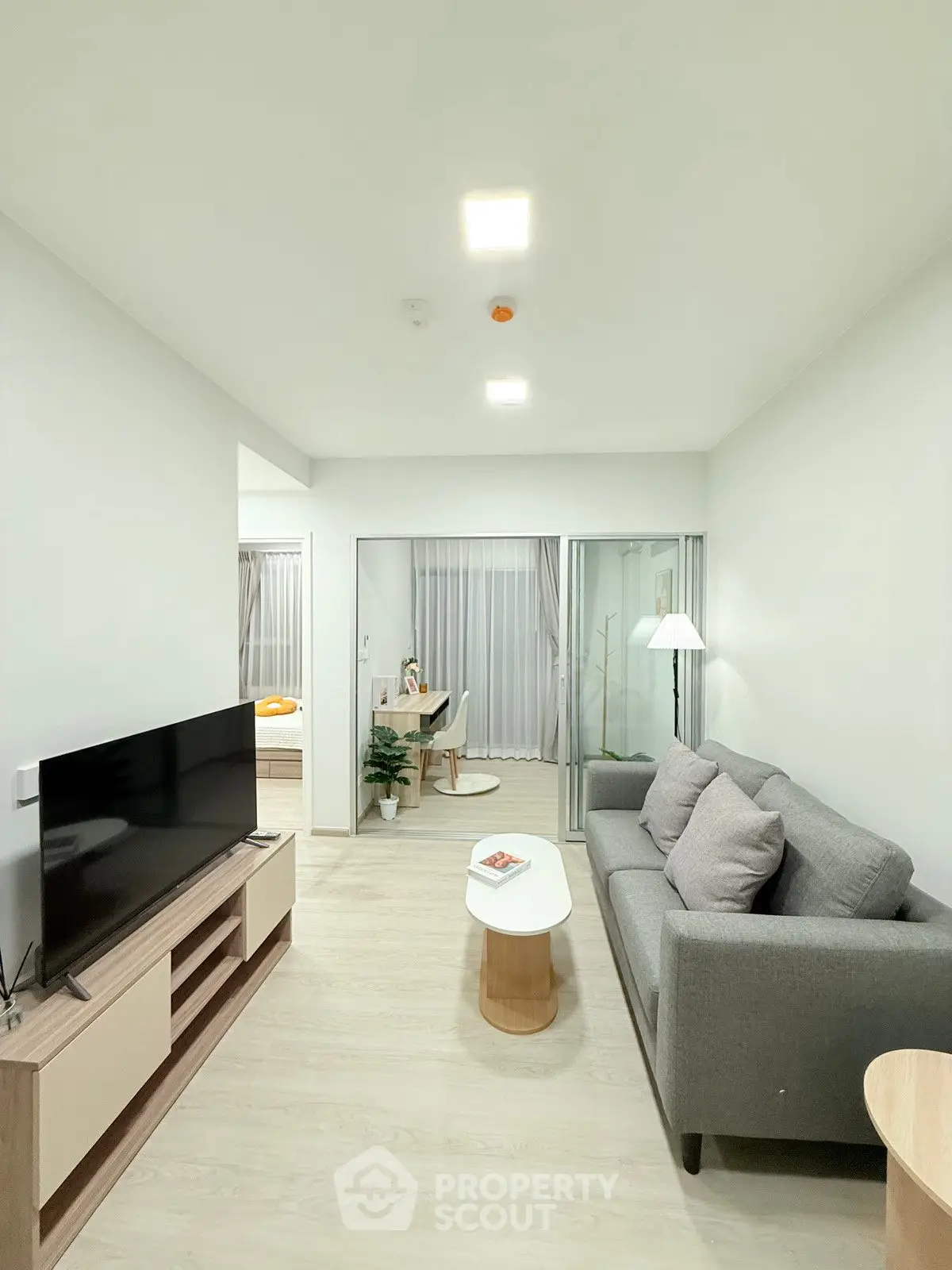 Modern living room with sleek furniture and open layout, featuring a cozy sofa and large TV.