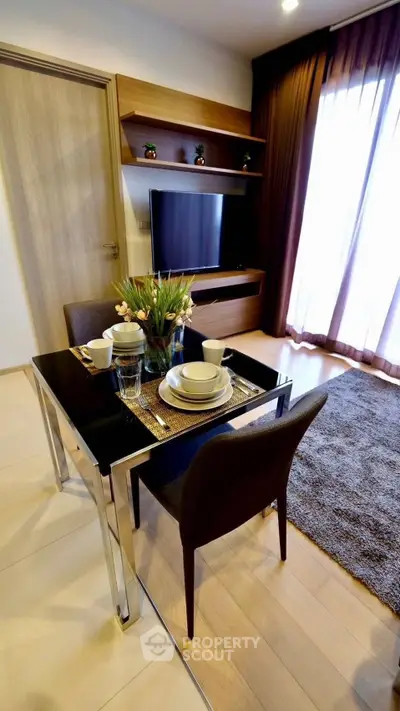 Modern dining area with sleek table, chairs, and TV in stylish apartment living room.
