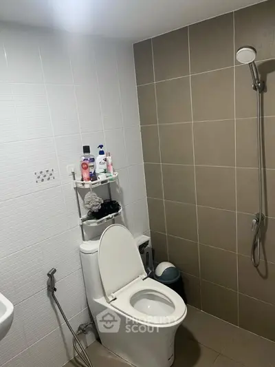 Modern bathroom with shower and toilet, featuring sleek tile design.
